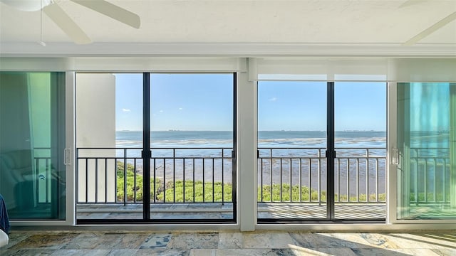 unfurnished sunroom with ceiling fan, a water view, and a view of the beach