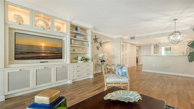 living area with hardwood / wood-style floors, built in shelves, crown molding, and an inviting chandelier