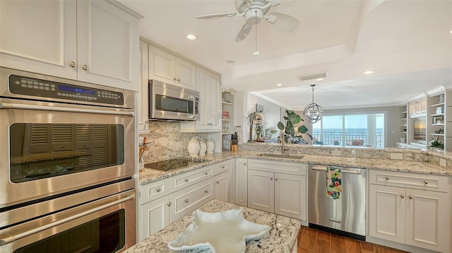 kitchen featuring sink, stainless steel appliances, tasteful backsplash, decorative light fixtures, and white cabinets