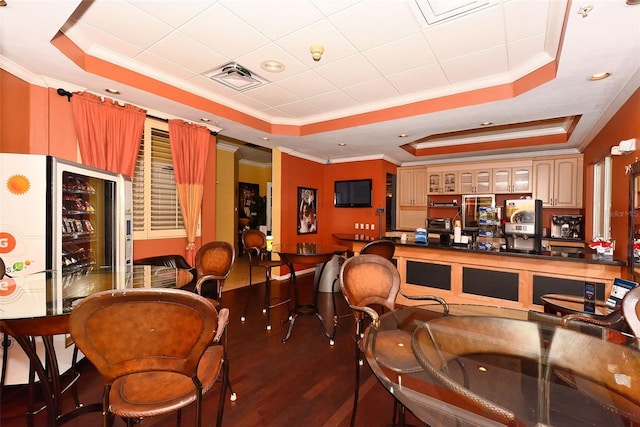 interior space featuring dark hardwood / wood-style floors, a raised ceiling, and ornamental molding