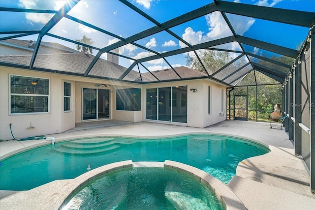 view of swimming pool featuring glass enclosure, an in ground hot tub, and a patio area