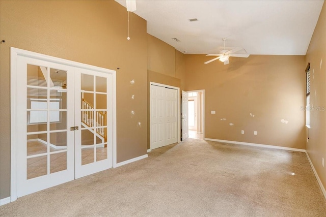 carpeted spare room with ceiling fan, french doors, and high vaulted ceiling