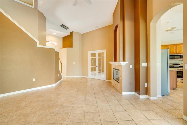 unfurnished living room featuring ceiling fan, light tile patterned floors, and high vaulted ceiling