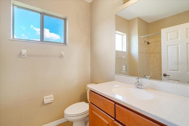 bathroom with a tile shower, vanity, a healthy amount of sunlight, and toilet