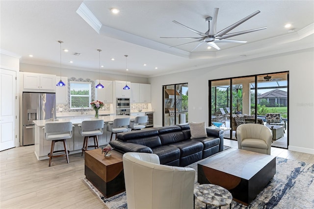 living room featuring plenty of natural light, ornamental molding, and a tray ceiling