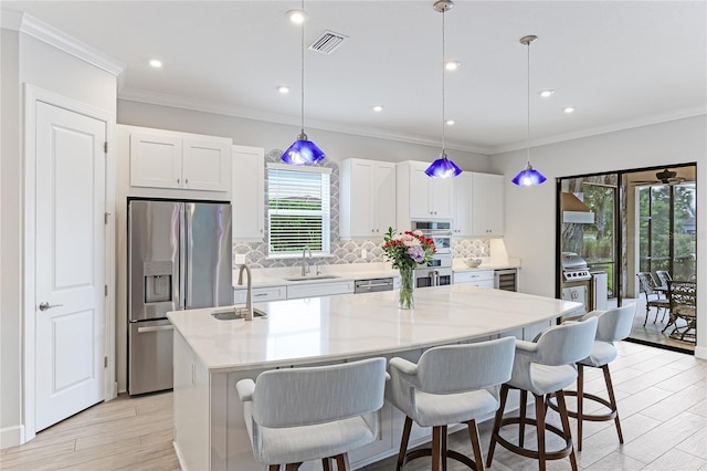 kitchen with a center island with sink, white cabinets, sink, and appliances with stainless steel finishes