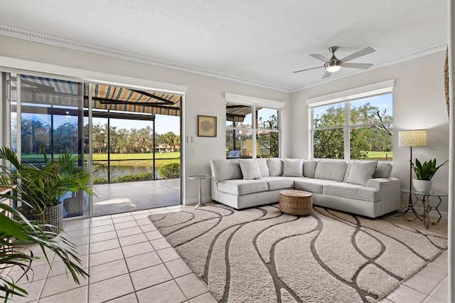 tiled living room featuring a water view, ornamental molding, a healthy amount of sunlight, and ceiling fan