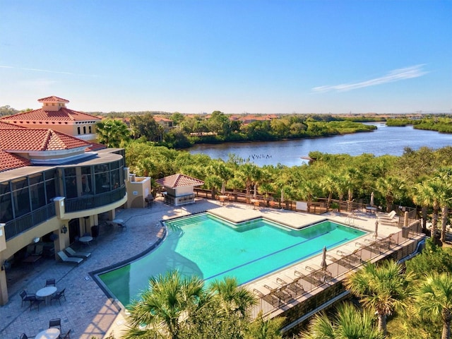 community pool with a water view, fence, and a patio