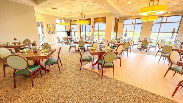 dining room featuring light wood-type flooring, plenty of natural light, a raised ceiling, and recessed lighting