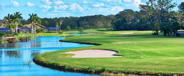 view of home's community with view of golf course, a water view, and a yard