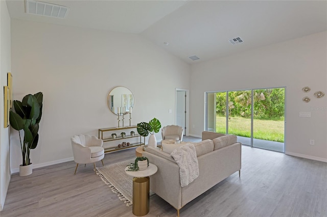 living room featuring high vaulted ceiling and light hardwood / wood-style flooring