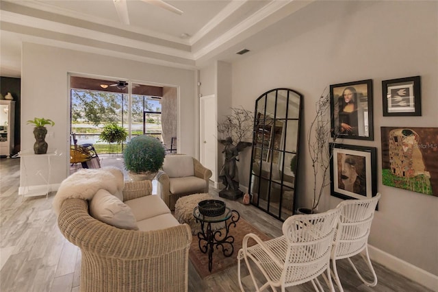 living room with ceiling fan, a raised ceiling, and wood-type flooring