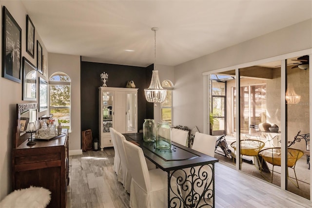 dining room featuring light hardwood / wood-style floors, a healthy amount of sunlight, and an inviting chandelier