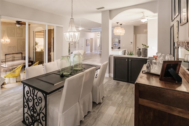 dining room with ceiling fan with notable chandelier and light wood-type flooring