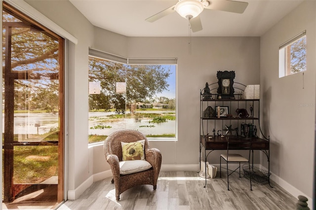 living area with ceiling fan, light hardwood / wood-style flooring, and a water view