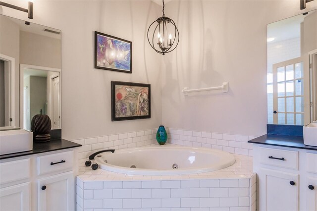 bathroom with vanity, tiled bath, and a notable chandelier