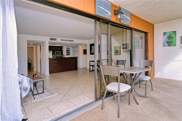 carpeted dining room with a textured ceiling