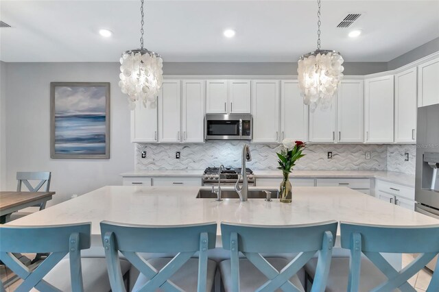 kitchen with decorative light fixtures, a center island with sink, a breakfast bar, an inviting chandelier, and appliances with stainless steel finishes