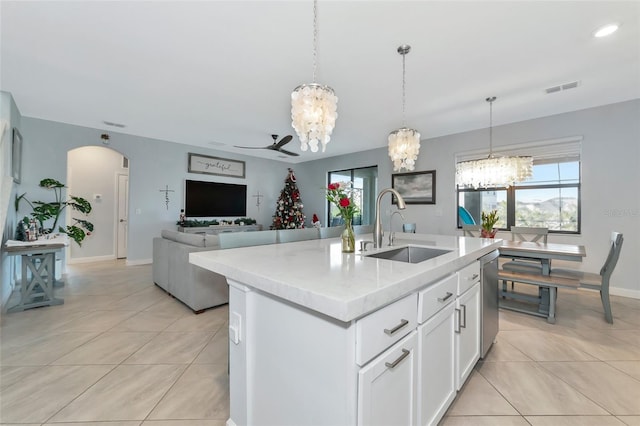 kitchen featuring light tile patterned floors, a center island with sink, ceiling fan with notable chandelier, white cabinets, and sink