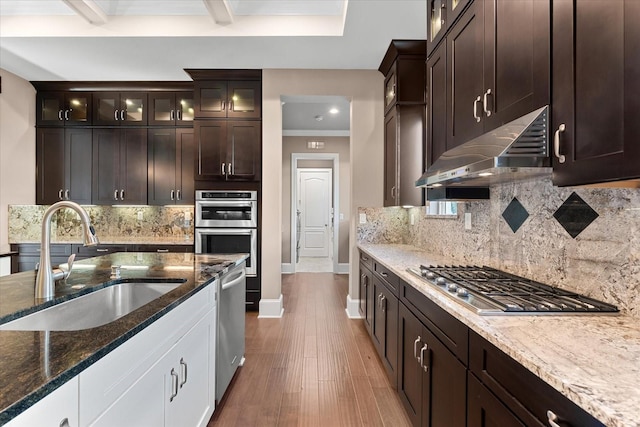 kitchen with backsplash, dark stone counters, stainless steel appliances, sink, and hardwood / wood-style floors