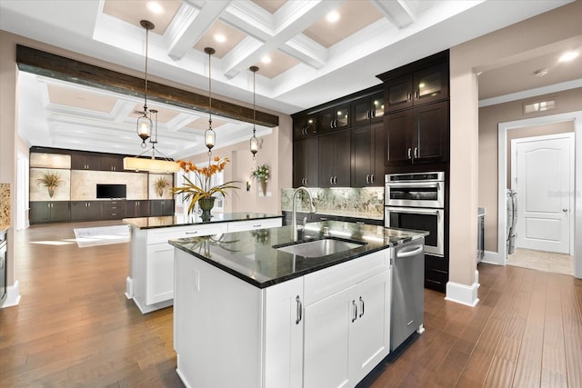 kitchen featuring sink, an island with sink, hanging light fixtures, and wood-type flooring