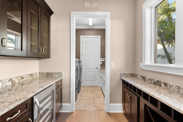 kitchen with washer and dryer, dark brown cabinetry, light hardwood / wood-style flooring, and beverage cooler