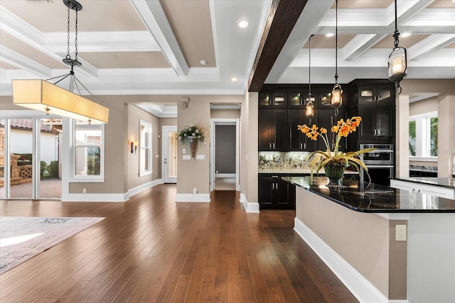 kitchen with dark stone countertops, a center island, decorative light fixtures, and dark hardwood / wood-style floors