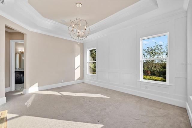 spare room featuring a raised ceiling, ornamental molding, light carpet, and an inviting chandelier