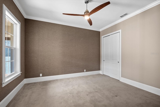 carpeted spare room with ceiling fan and crown molding