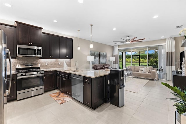 kitchen featuring pendant lighting, sink, backsplash, stainless steel appliances, and light stone counters