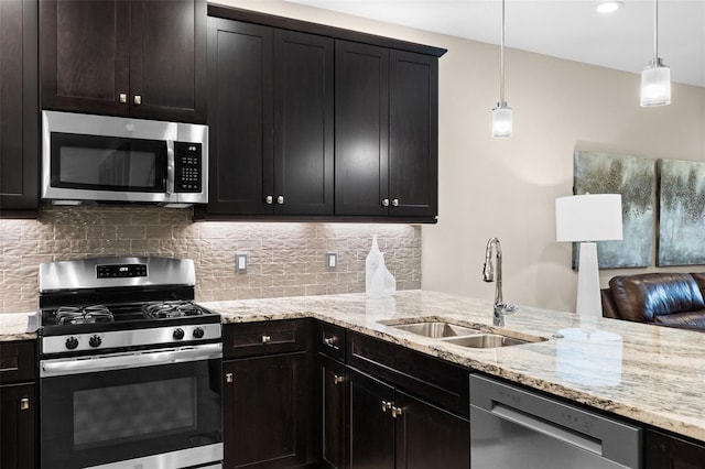 kitchen featuring sink, light stone counters, tasteful backsplash, appliances with stainless steel finishes, and pendant lighting