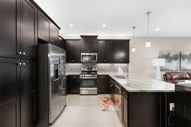 kitchen with appliances with stainless steel finishes, decorative light fixtures, tasteful backsplash, sink, and dark brown cabinets