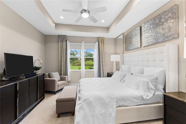 bedroom featuring light carpet, a raised ceiling, and ceiling fan