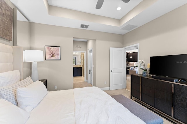 bedroom with ceiling fan, connected bathroom, and a raised ceiling