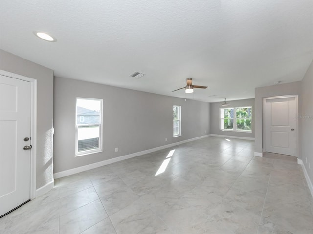 unfurnished room with ceiling fan, a textured ceiling, and a wealth of natural light