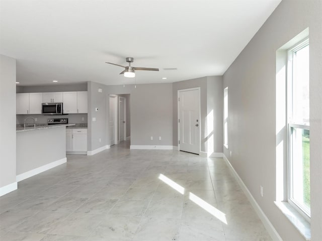 unfurnished living room with ceiling fan and sink