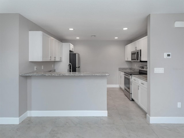 kitchen featuring kitchen peninsula, appliances with stainless steel finishes, white cabinetry, and light stone counters