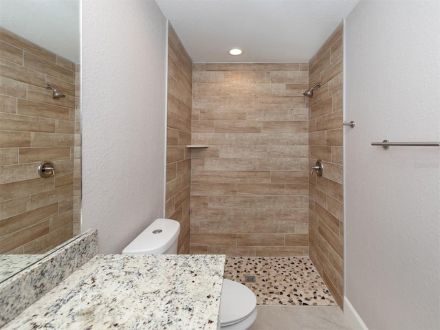 bathroom featuring vanity, toilet, and tiled shower