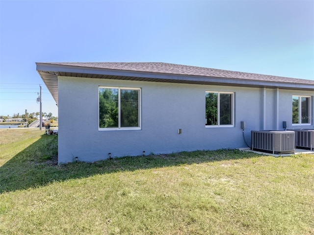 rear view of house with central AC unit and a yard