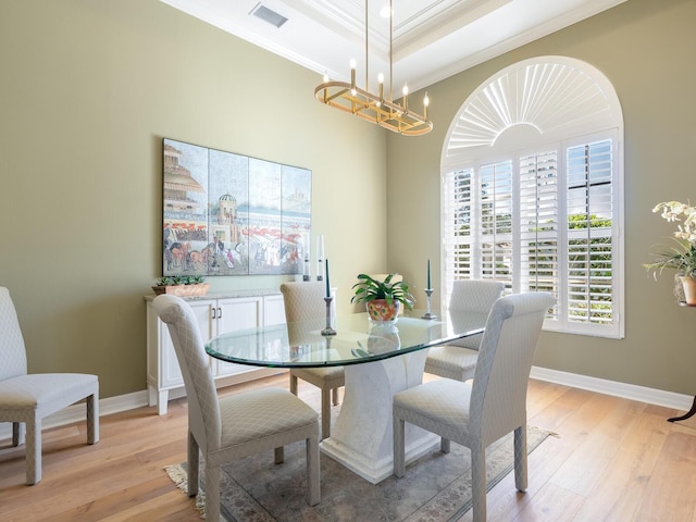 dining space featuring a tray ceiling, ornamental molding, light hardwood / wood-style floors, and a notable chandelier