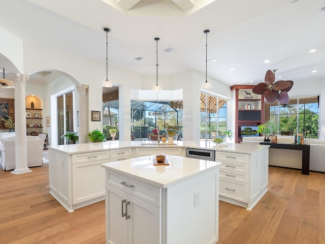 kitchen featuring pendant lighting, a center island, ceiling fan, white cabinetry, and decorative columns