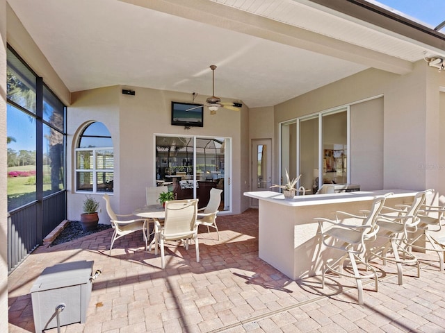 view of patio with ceiling fan and an outdoor bar