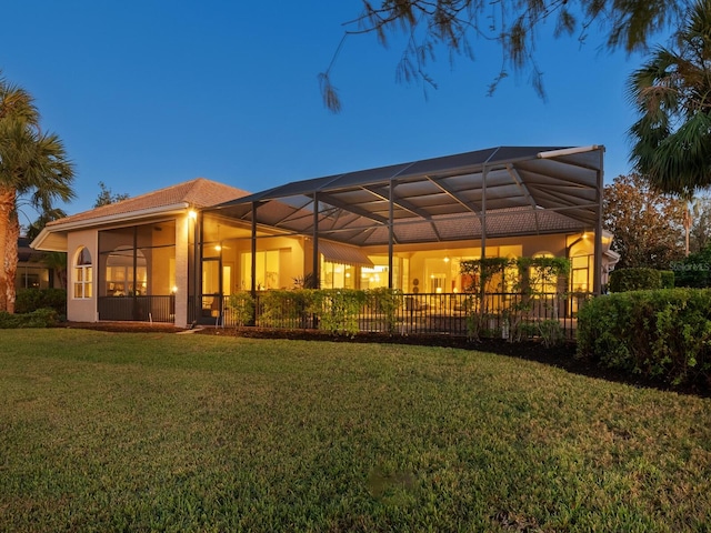 back of house with a lanai and a yard