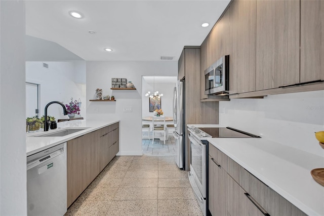 kitchen with appliances with stainless steel finishes, light brown cabinetry, a notable chandelier, and sink