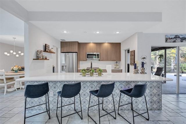 kitchen featuring hanging light fixtures, a notable chandelier, kitchen peninsula, a breakfast bar area, and appliances with stainless steel finishes