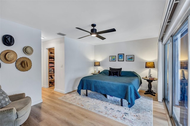 bedroom with a spacious closet, a closet, ceiling fan, and light hardwood / wood-style floors