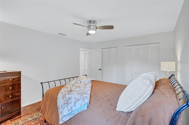 bedroom with ceiling fan, wood-type flooring, and two closets