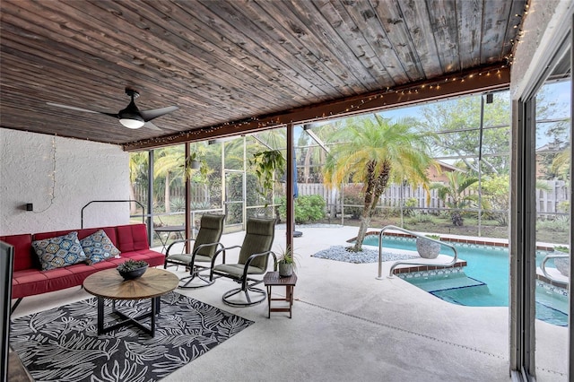 exterior space featuring glass enclosure, ceiling fan, a fenced in pool, and an outdoor hangout area