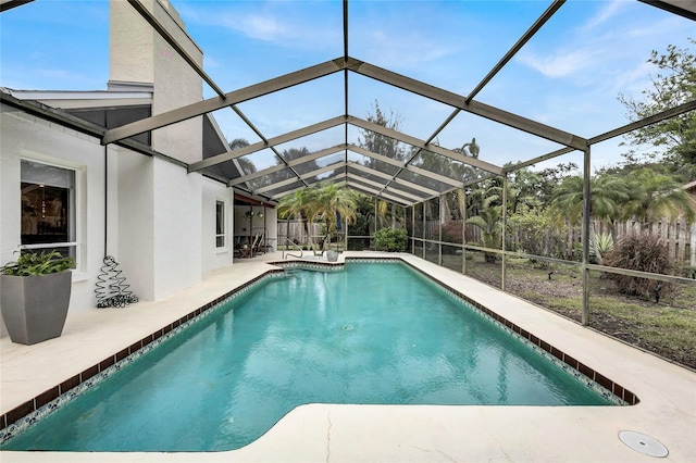 view of pool with glass enclosure and a patio area