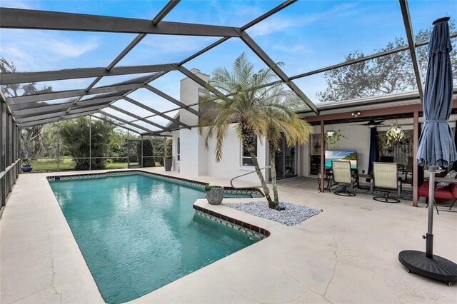 view of pool featuring ceiling fan, a patio area, and a lanai